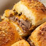 Sliders with roast beef and cheese inside the baking pan.
