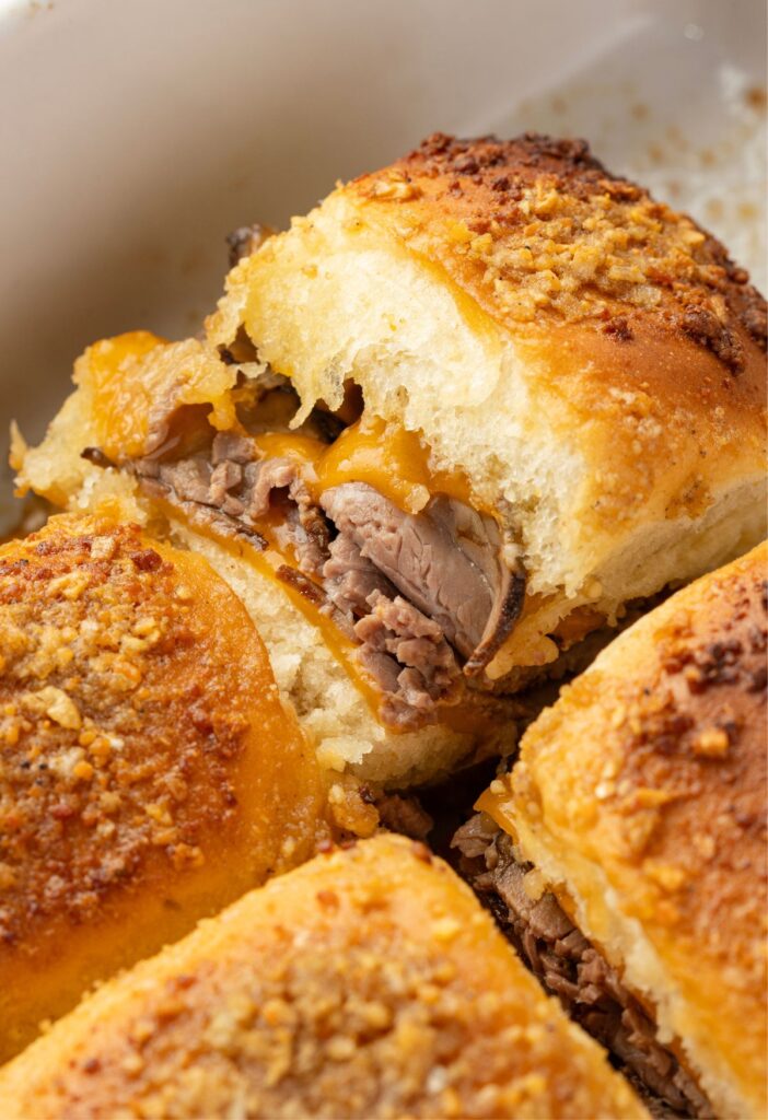 Sliders with roast beef and cheese inside the baking pan.