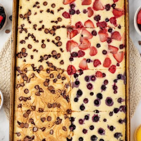 Sheet pan with the pancakes on it with different toppings on each part.