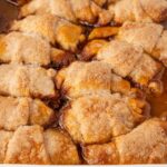 A white baking pan of the baked apple dumplings inside of it.