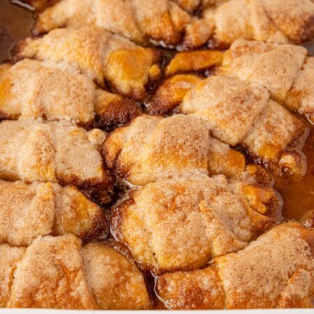 A white baking pan of the baked apple dumplings inside of it.