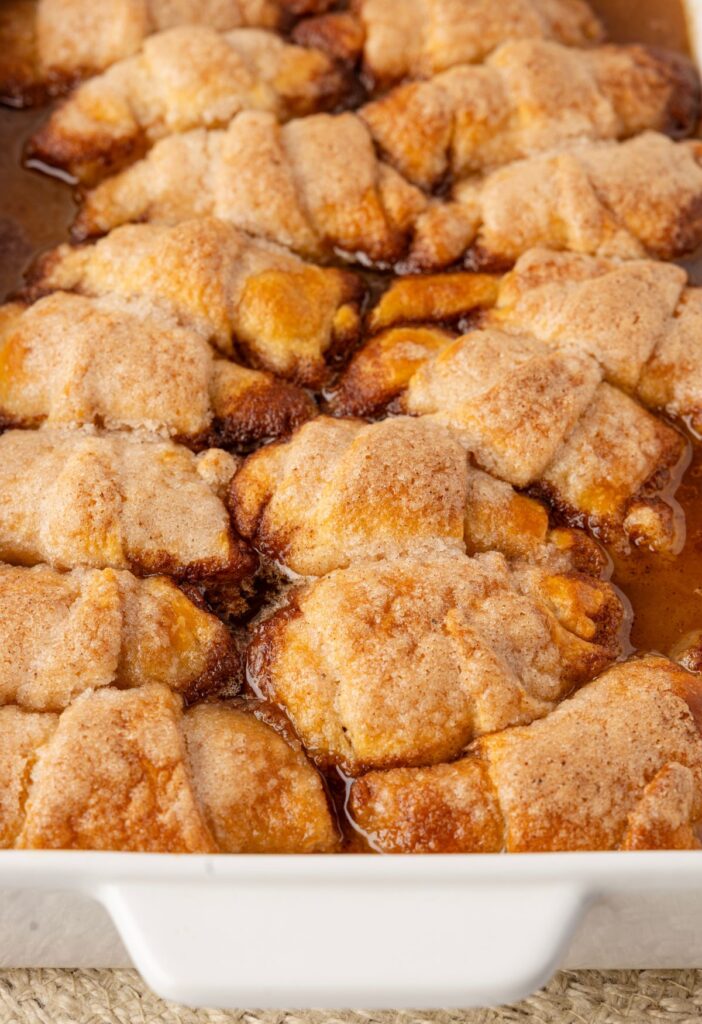 A white baking pan of the baked apple dumplings inside of it.
