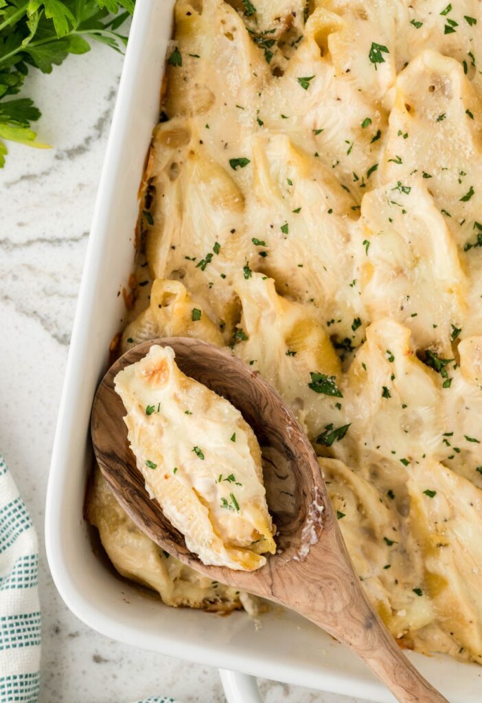 Stuffed shells casserole dish with a serving spoon in it