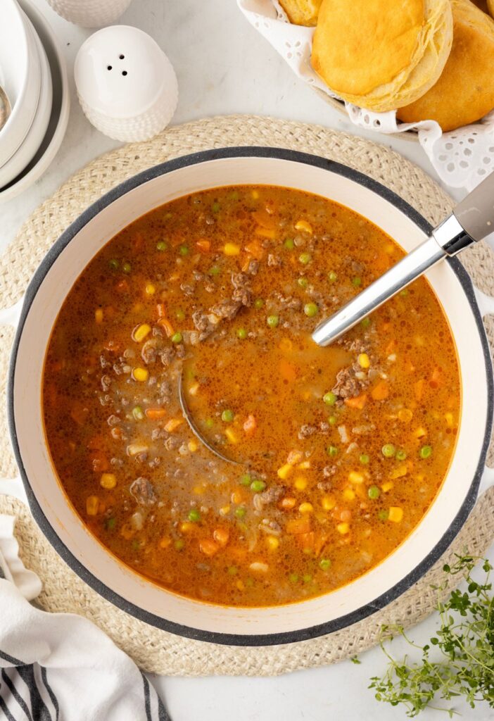 A soup pot with a soup ladle in it and fresh thyme sprigs to the side. 