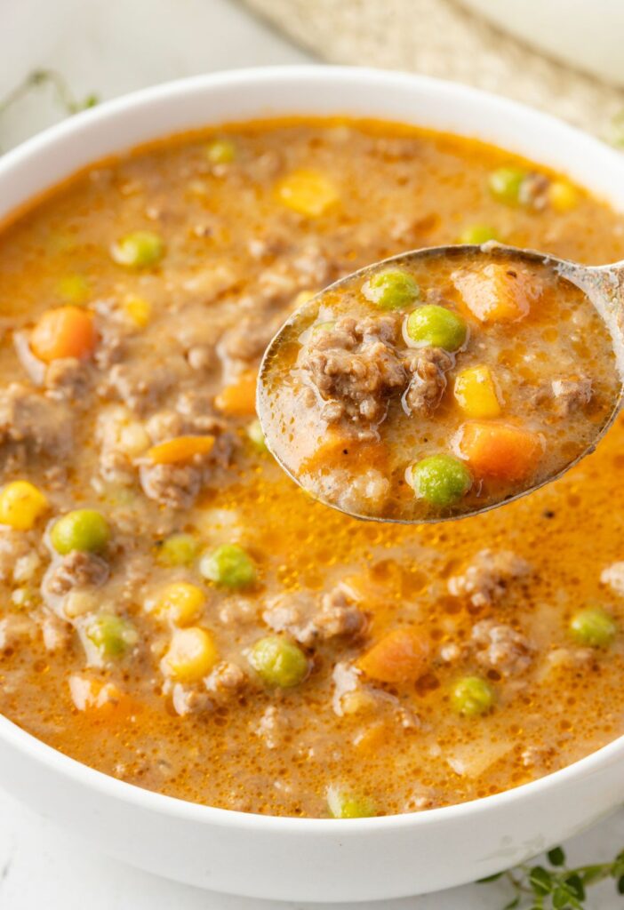 A bowl of shepherds pie soup with a spoon in it.