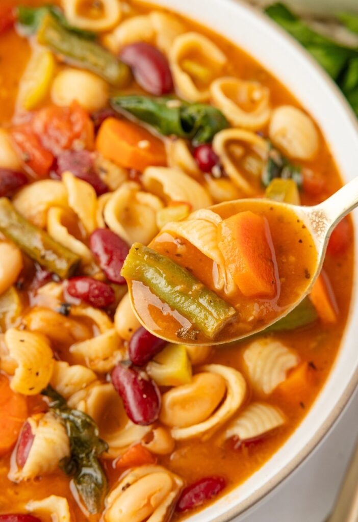 A bowl of soup with a spoon holding some of it on it. 