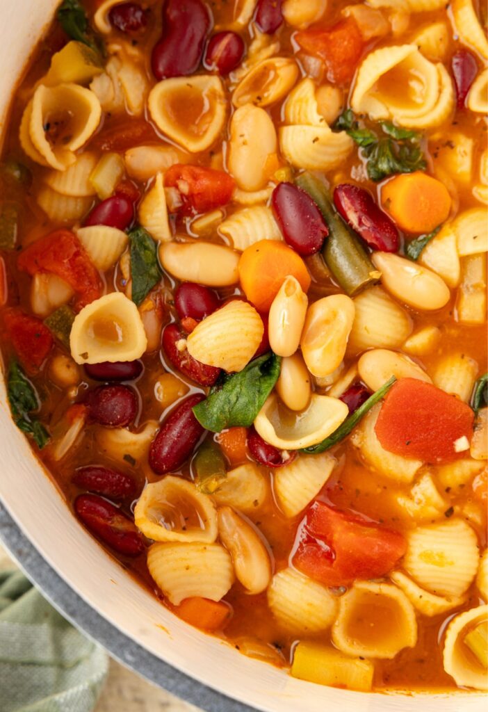 Top view of the soup pot with the cooked minestrone soup inside of it. 