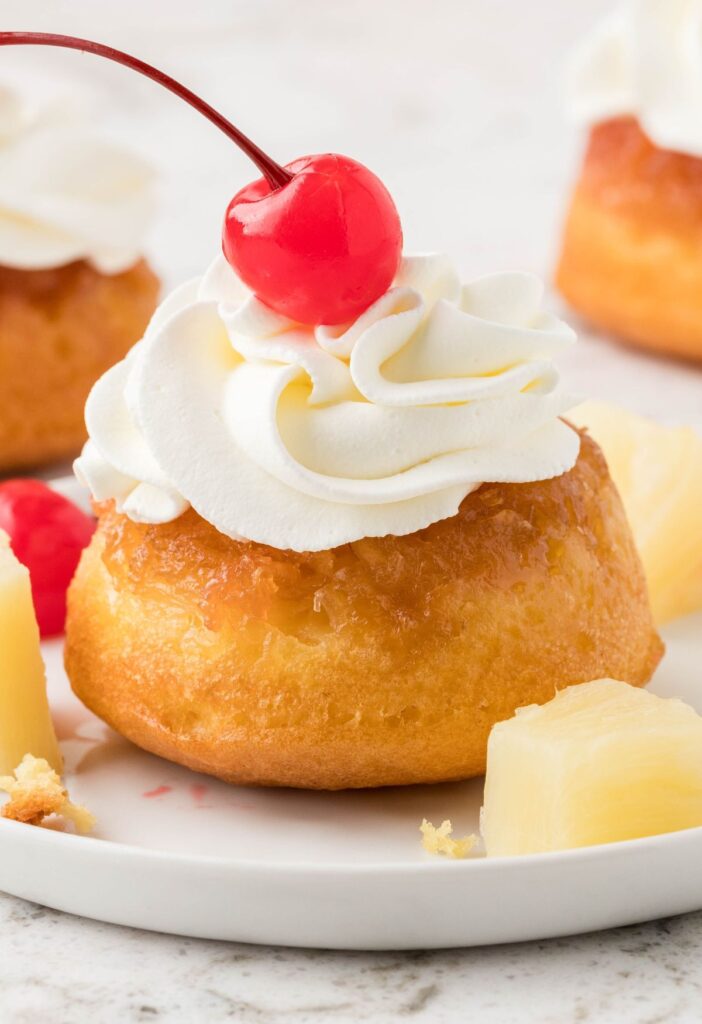 hero shot for the mini cakes (pineapple upside down cupcakes) with whipped cream and a cherry on top.