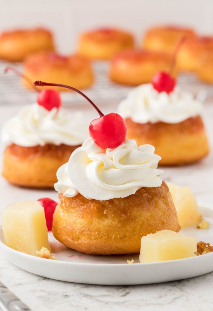 hero shot for the mini cakes (pineapple upside down cupcakes) with whipped cream and a cherry on top.