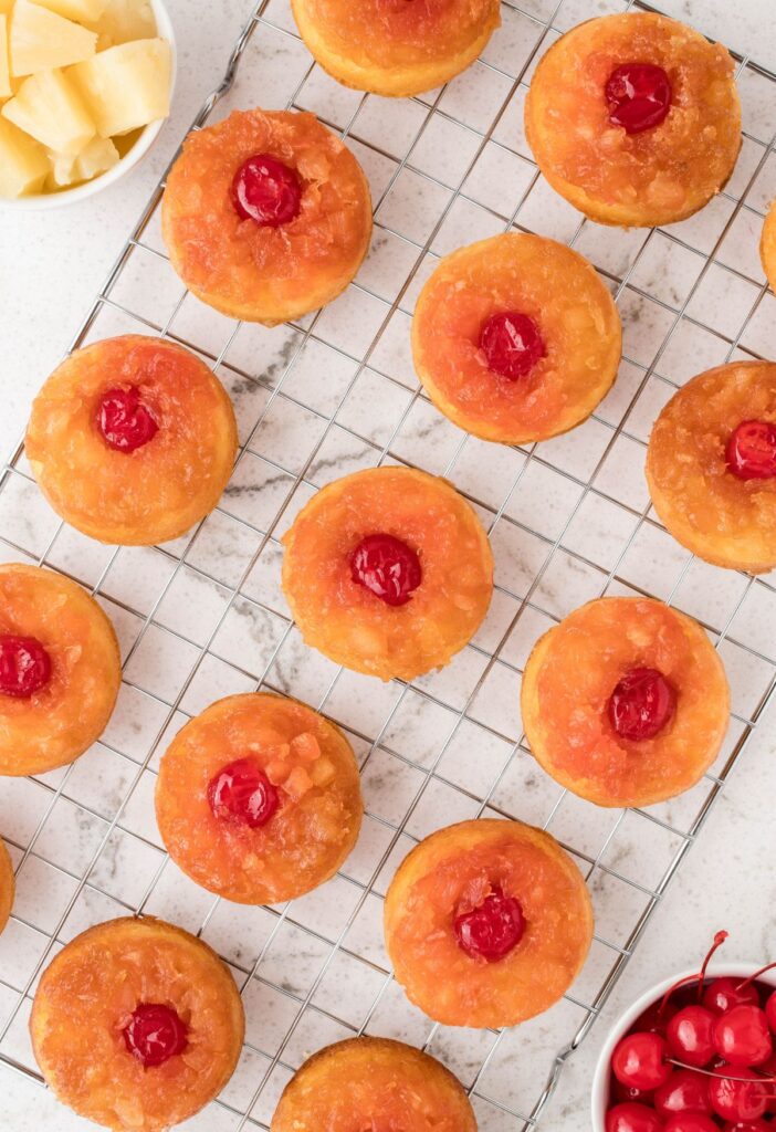 The baked mini cakes with pineapple and cherries, on a cooling rack. 