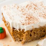 A slice of tres leches cake with pumpkin on a white plate with a fork.