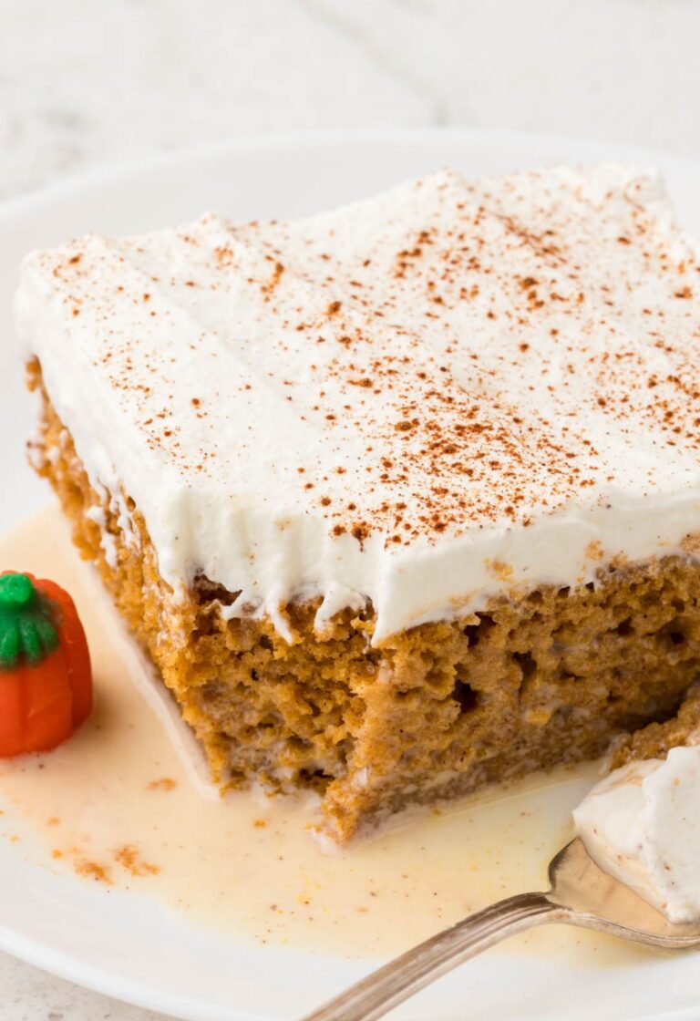 A slice of tres leches cake with pumpkin on a white plate with a fork.