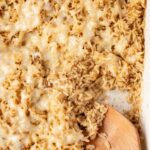 A pan of the baked rice in it with a wooden spoon
