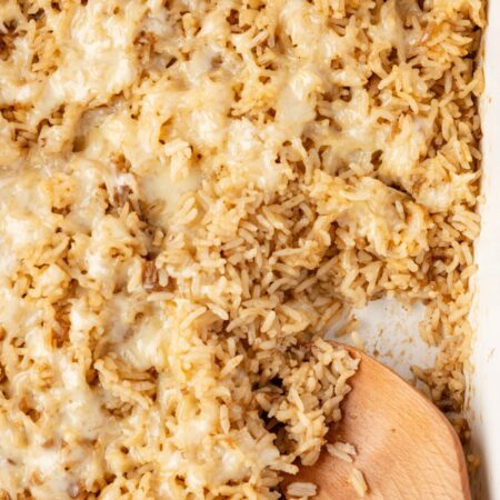 A pan of the baked rice in it with a wooden spoon