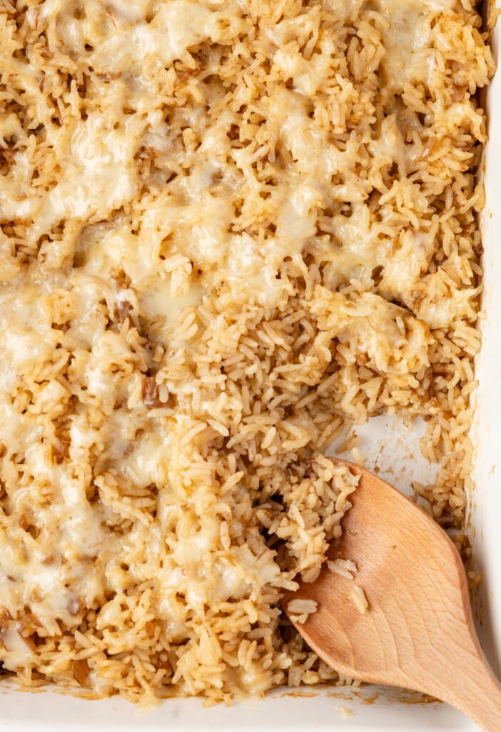 A pan of the baked rice in it with a wooden spoon