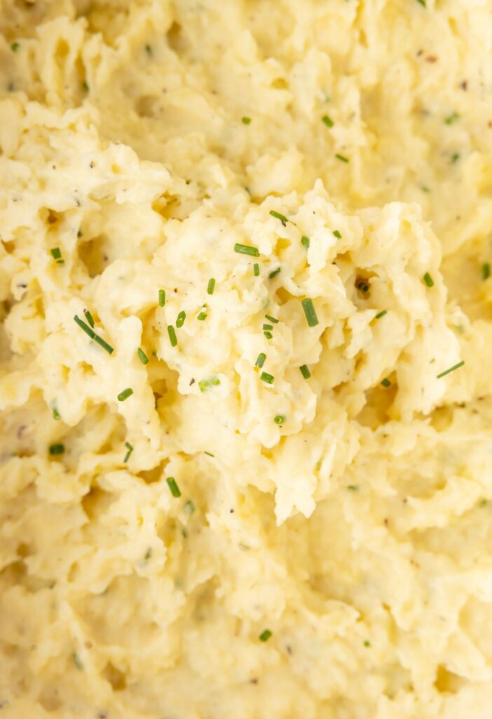 Close up of creamy mashed potatoes with chives on top. 