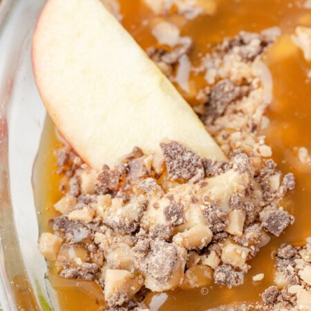 An apple slice inside the caramel apple fruit dip in a pie plate.