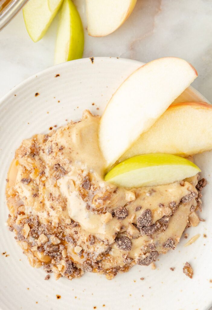 Fruit dip on a plate with apple slices around it. 