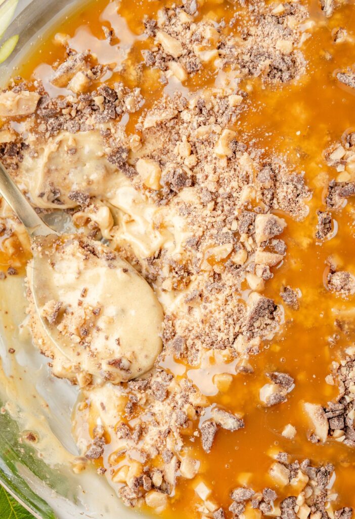 A pie plate of caramel apple apple dip with a spoon in it. 
