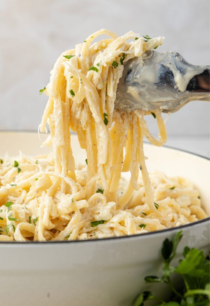 Tongs with some of the cream cheese pasta on it