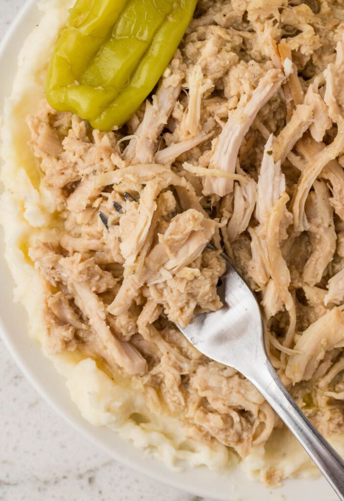 Serving of the Mississippi chicken with a fork over some mashed potatoes. 