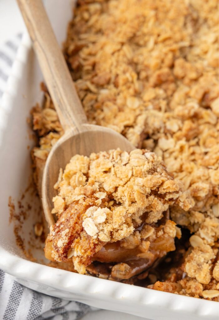 Scoop of the pear crisp on a wooden spoon