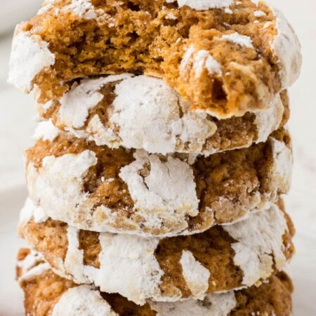 Stack of pumpkin cookies with crinkle powdered sugar