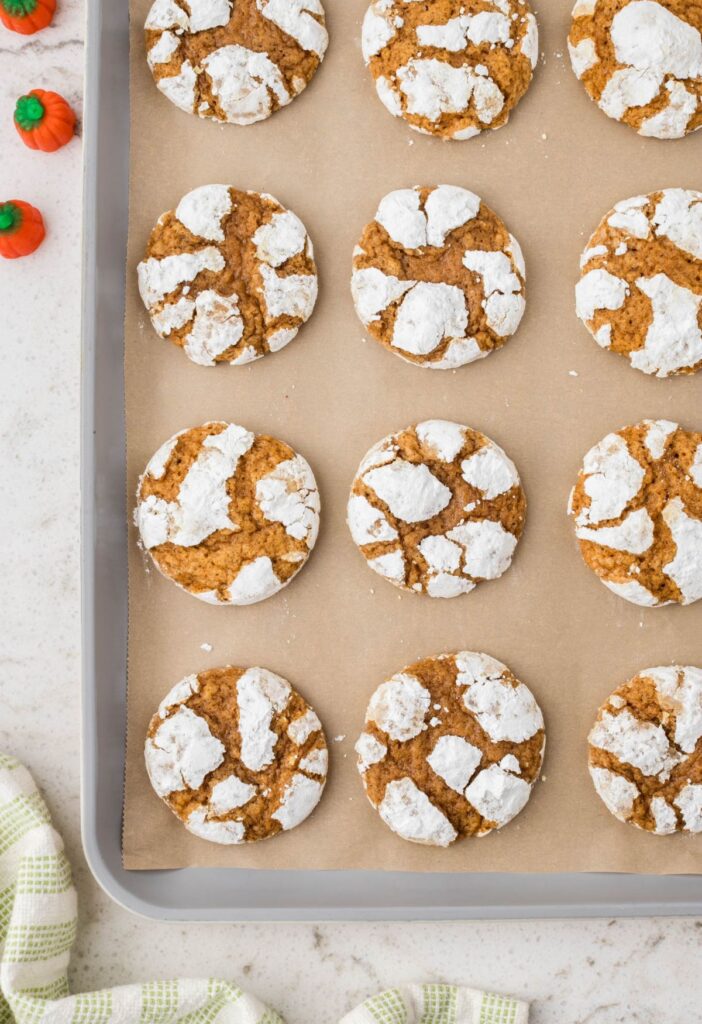 Crinkle pumpkin cookies on a cookie sheet with parchment paper. 