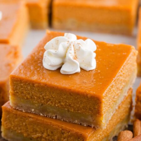 A stack of two pumpkin pie bars with whipped cream on top