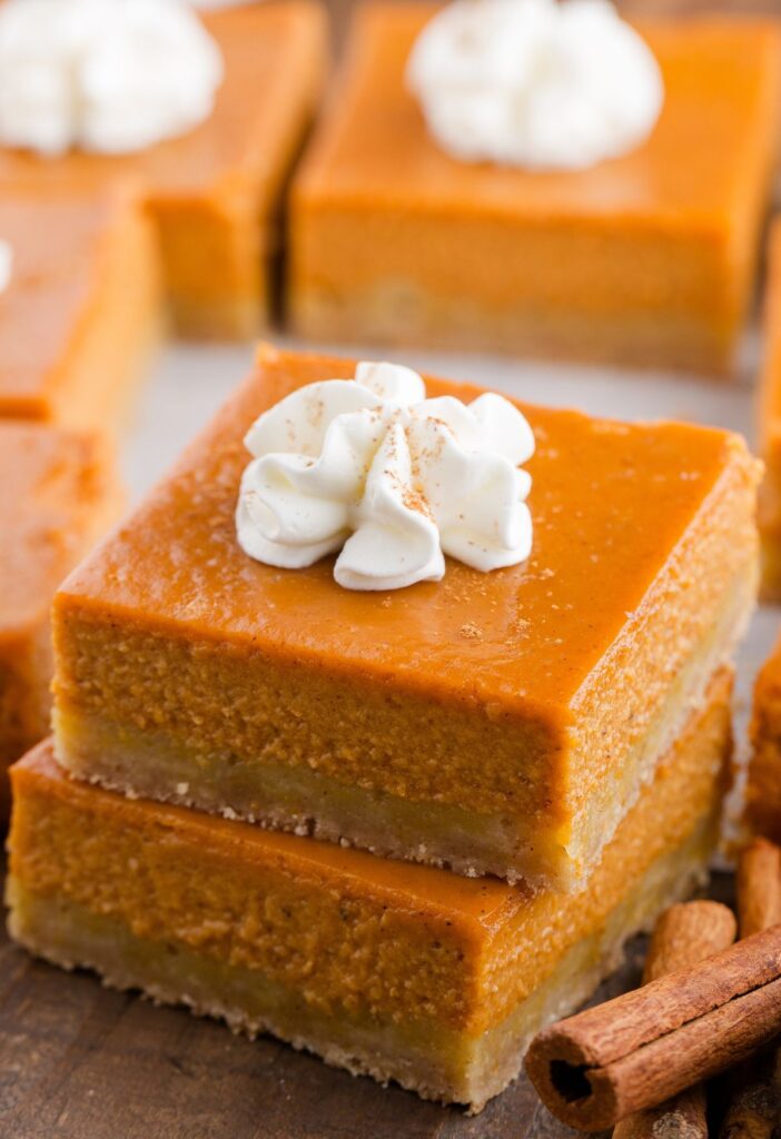 A stack of two pumpkin pie bars with whipped cream on top