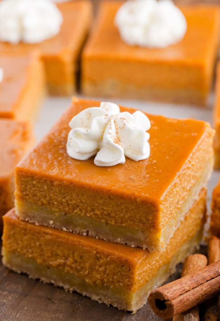A stack of two pumpkin pie bars with whipped cream on top