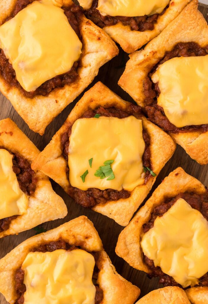 Top view of the cheese on top of the sloppy Joe filling inside the crescent dough cups. 