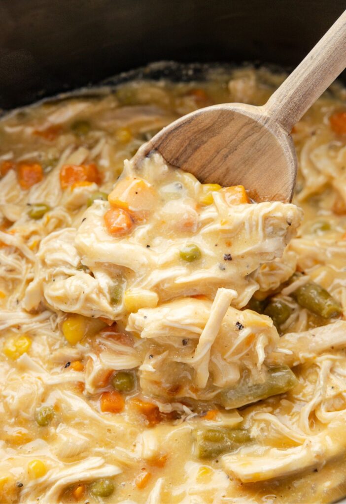 A wooden serving spoon with chicken pot pie on it