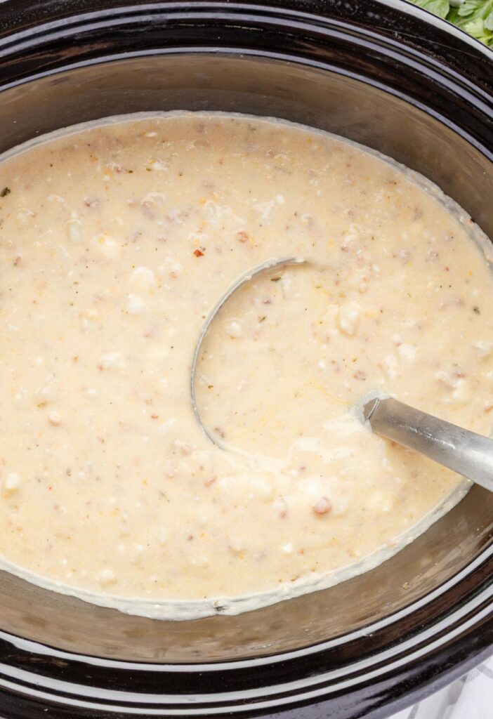 Potato soup inside the slow cooker with a ladle