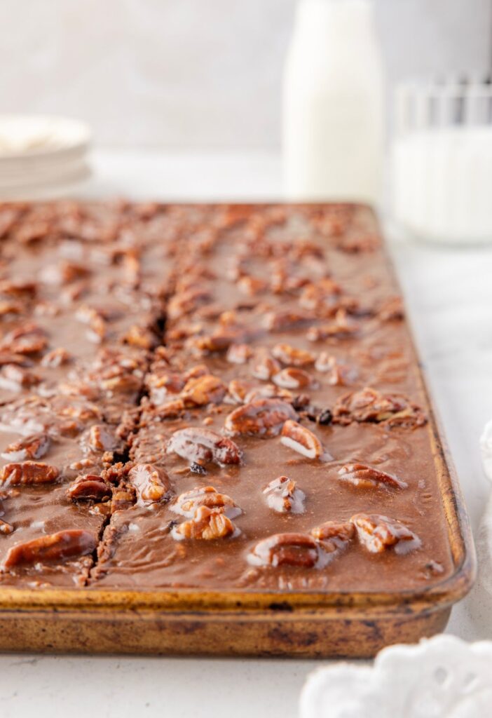 Side view of the sheet pan with the chocolate Texas cake in it and a glass of milk. 