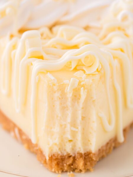 A front view of a slice of cheesecake with a fork bite taken out of the front