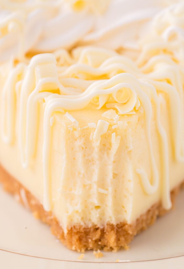 A front view of a slice of cheesecake with a fork bite taken out of the front