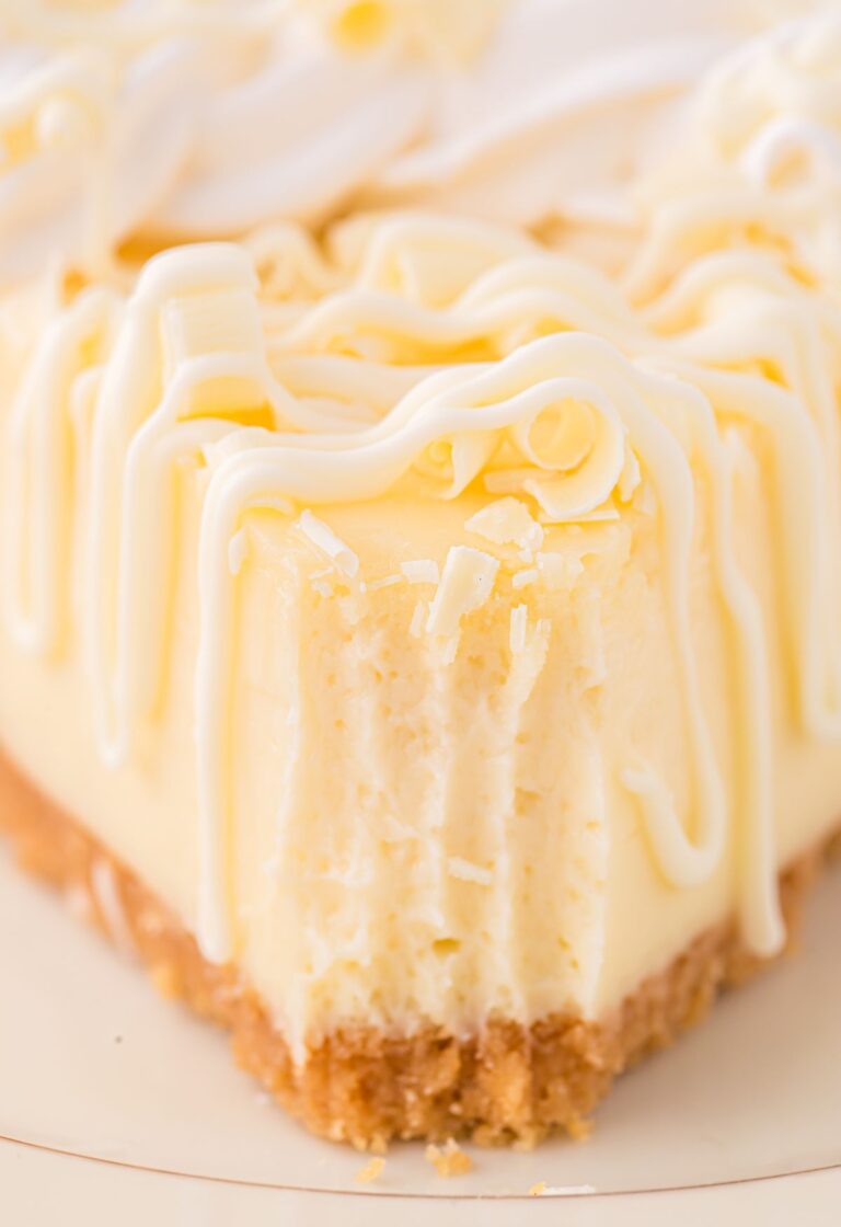 A front view of a slice of cheesecake with a fork bite taken out of the front