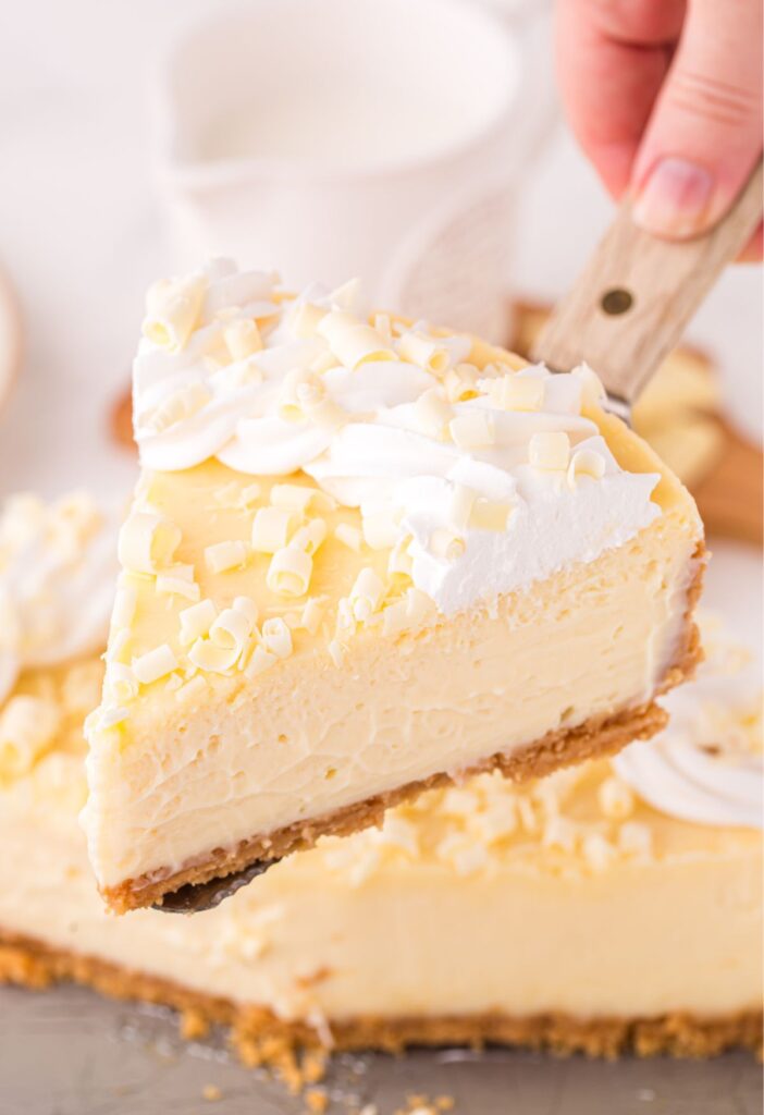 A serving spatula with a slice of white chocolate cheesecake on it