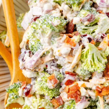 Close up of the broccoli salad inside a serving bowl with a wooden spoon.