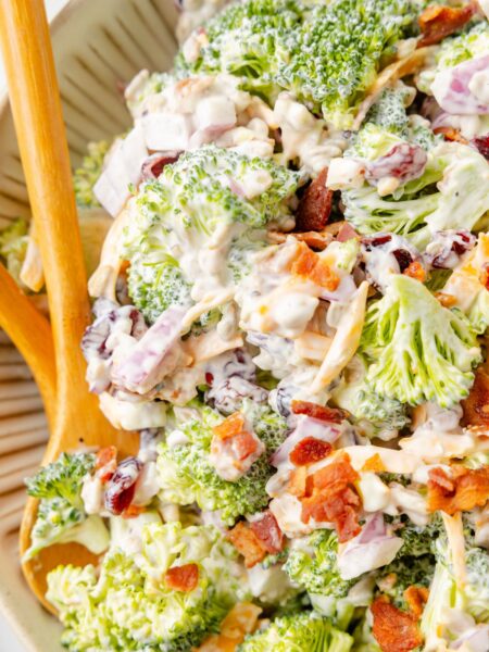 Close up of the broccoli salad inside a serving bowl with a wooden spoon.