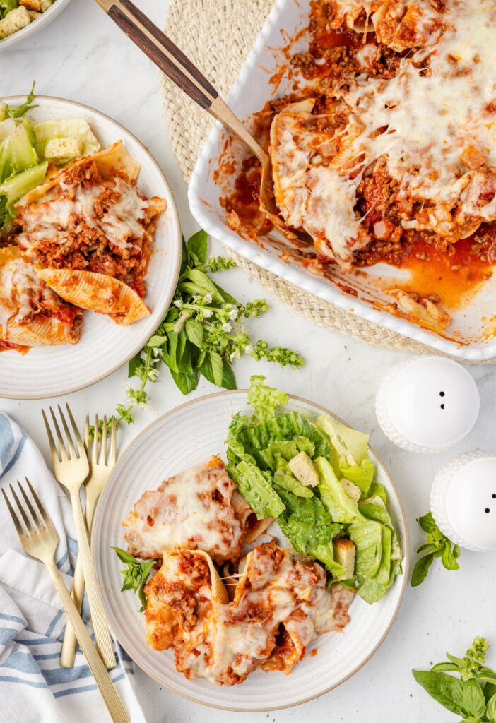 Overhead pic of the casserole pan with a serving plate of the stuffed shells