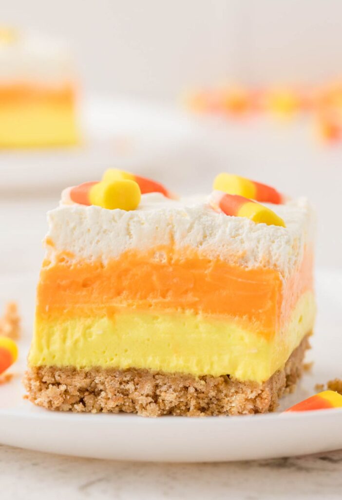 Slice of layered lush dessert with candy corn colors. 