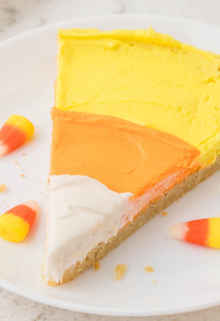 Slice of the candy corn dessert pizza with a sugar cookie crust