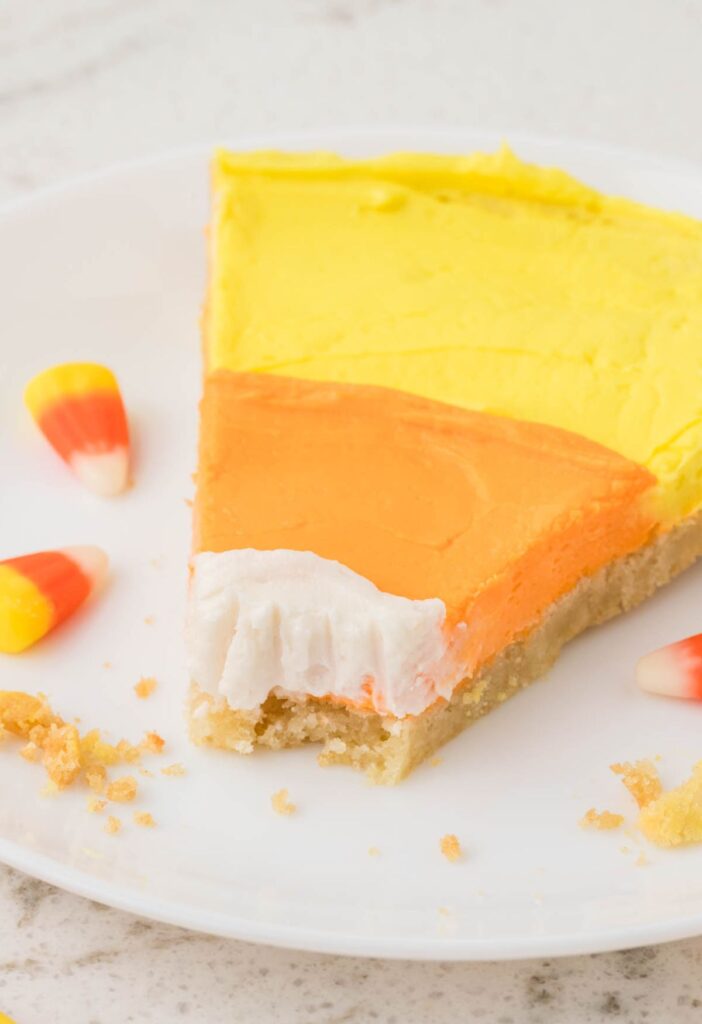 A slice of the sugar cookie pizza with candy corn frosting on it