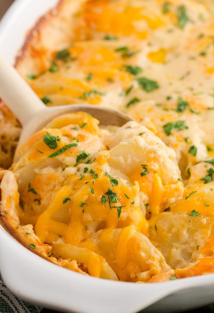 A scoop inside the casserole of scalloped potatoes with cheese on top. 