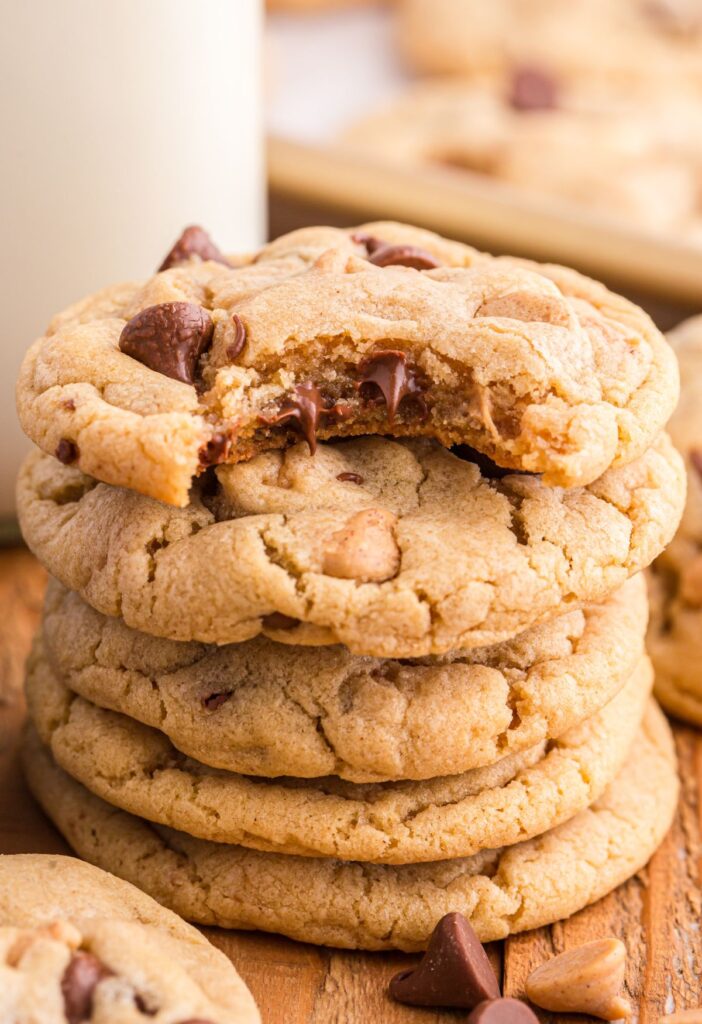 Stack of cookies on a wooden background with a glass of milk next to the stack. 