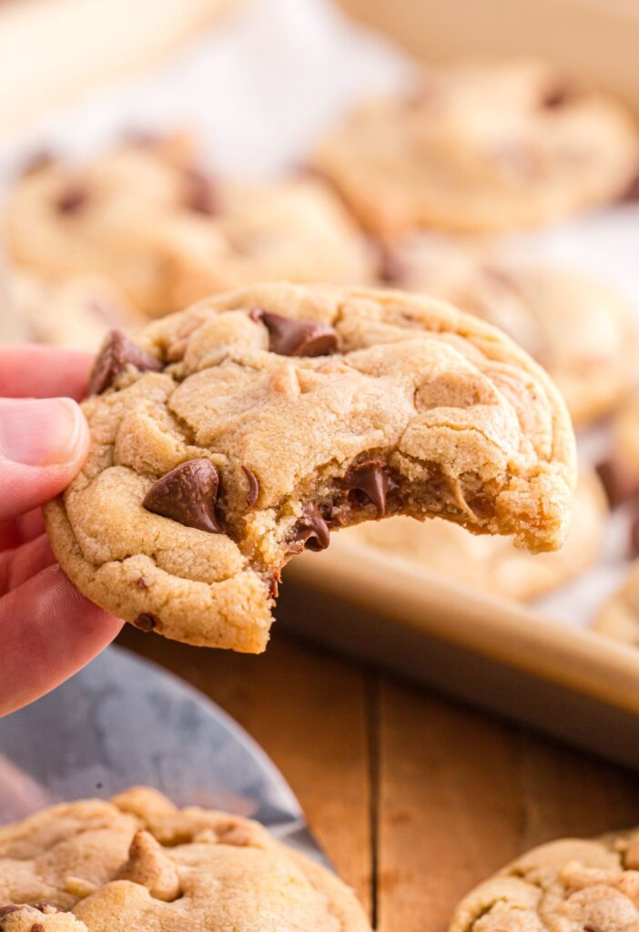 A hand holding a cookie with a bite taken out of it. 