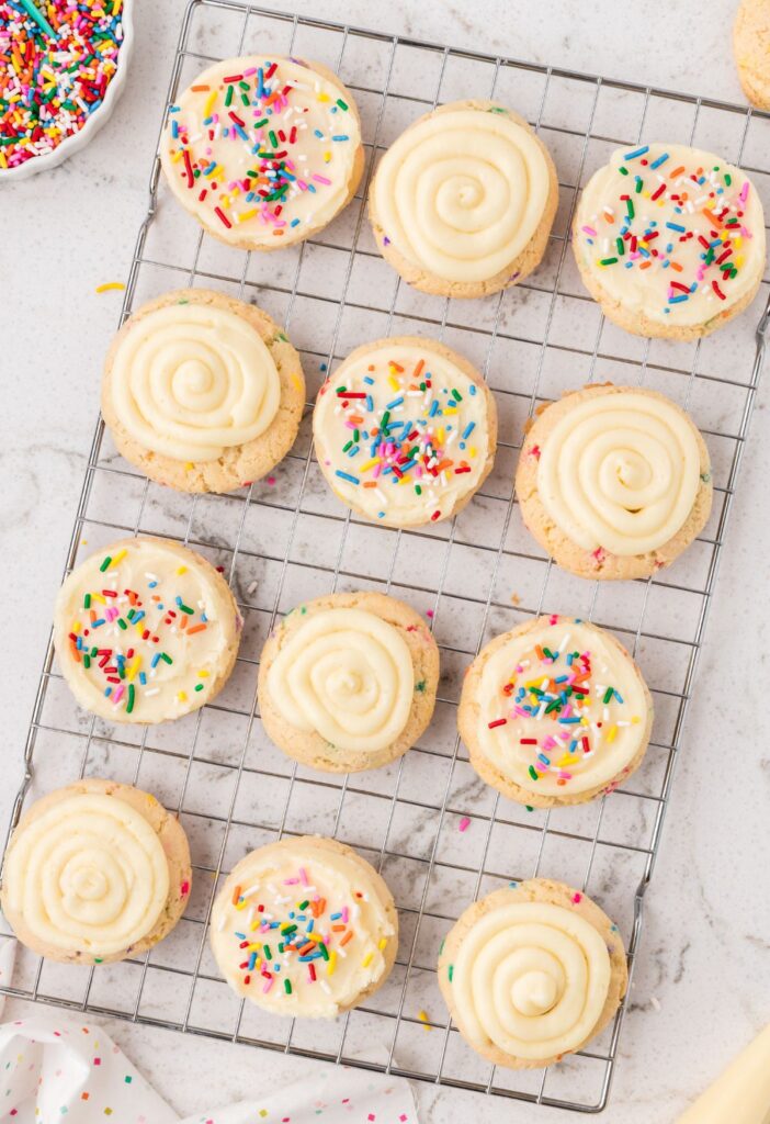 A cooling rack with the frosted funfetti cookies on it. 