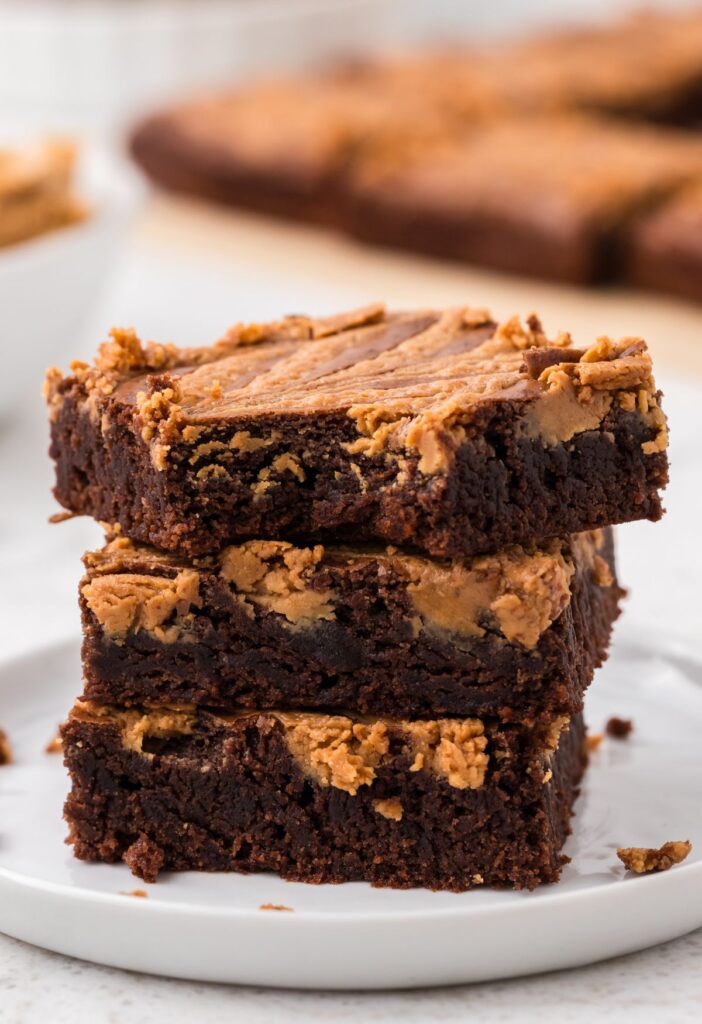 Stack of three brownies with the top brownie having a bite taken out of it. 
